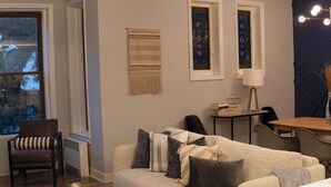 Un salon avec un canapé, un fauteuil et une petite table sur laquelle se trouvent des livres et une lampe.