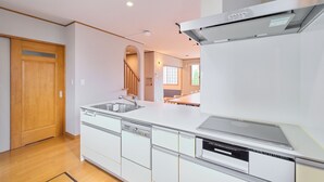 Una cocina moderna con electrodomésticos integrados, una puerta de madera y vistas al área de comedor.