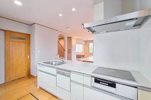 Eine moderne Küche mit eingebauten Geräten, einer Holztür und Blick zum Essbereich.