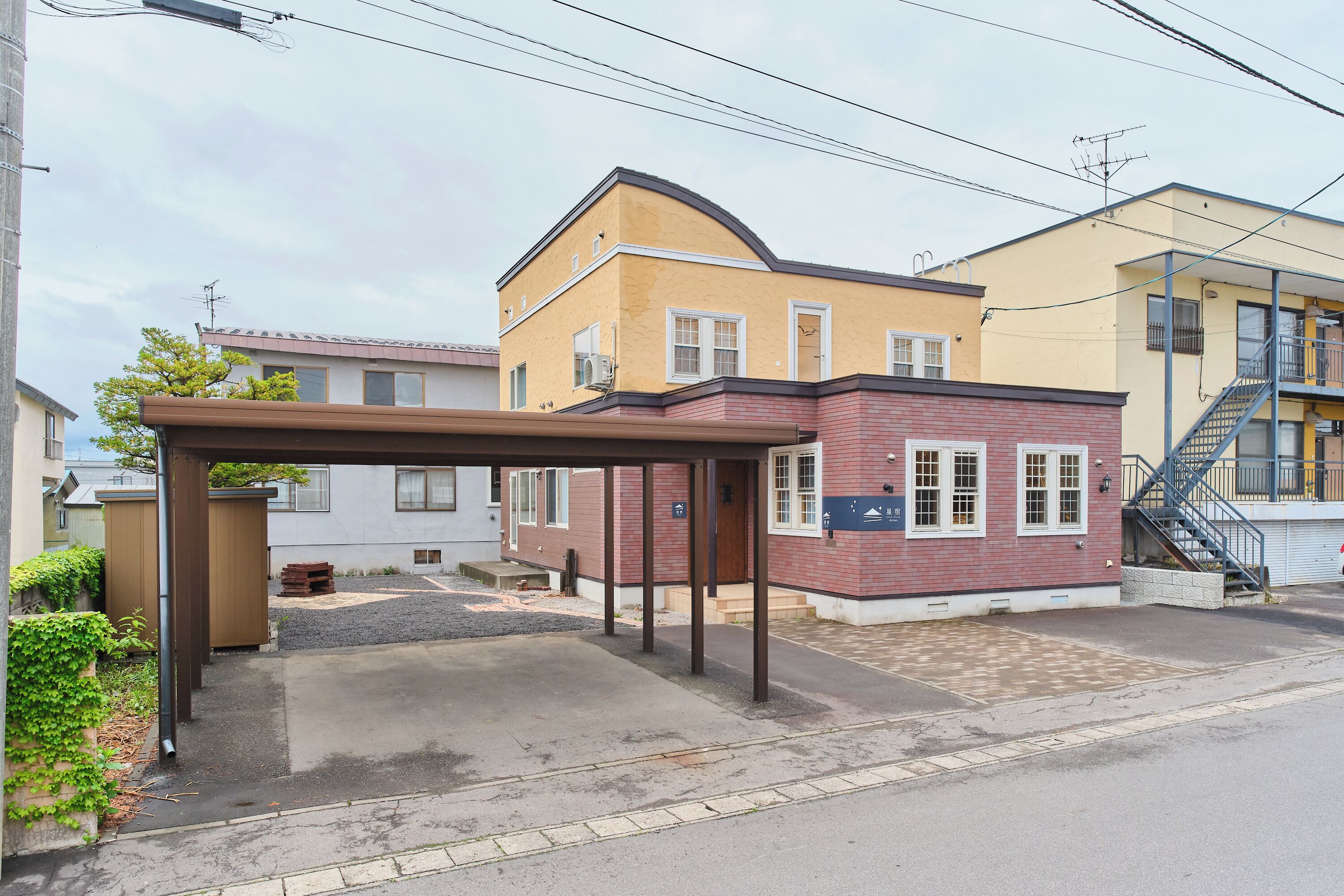 A residential building with a covered porch, a brick section, and a staircase leading to an upper level.