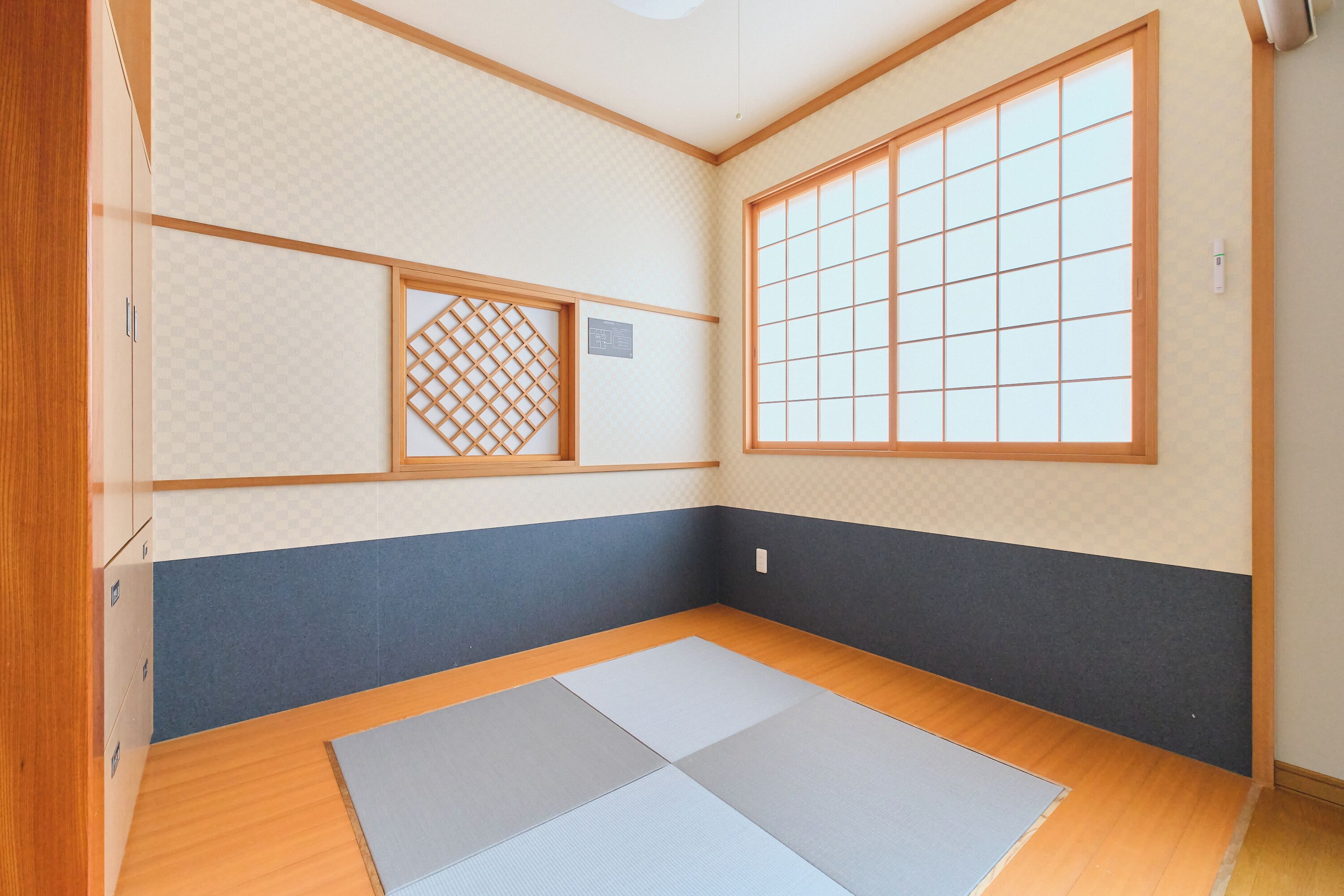 Una habitación con suelo de tatami, puertas correderas de shoji y un ventanal grande.