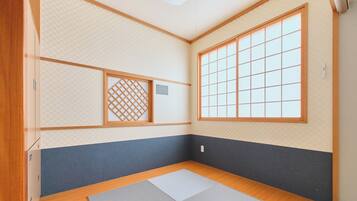 Una habitación con suelo de tatami, puertas correderas de shoji y un ventanal grande.