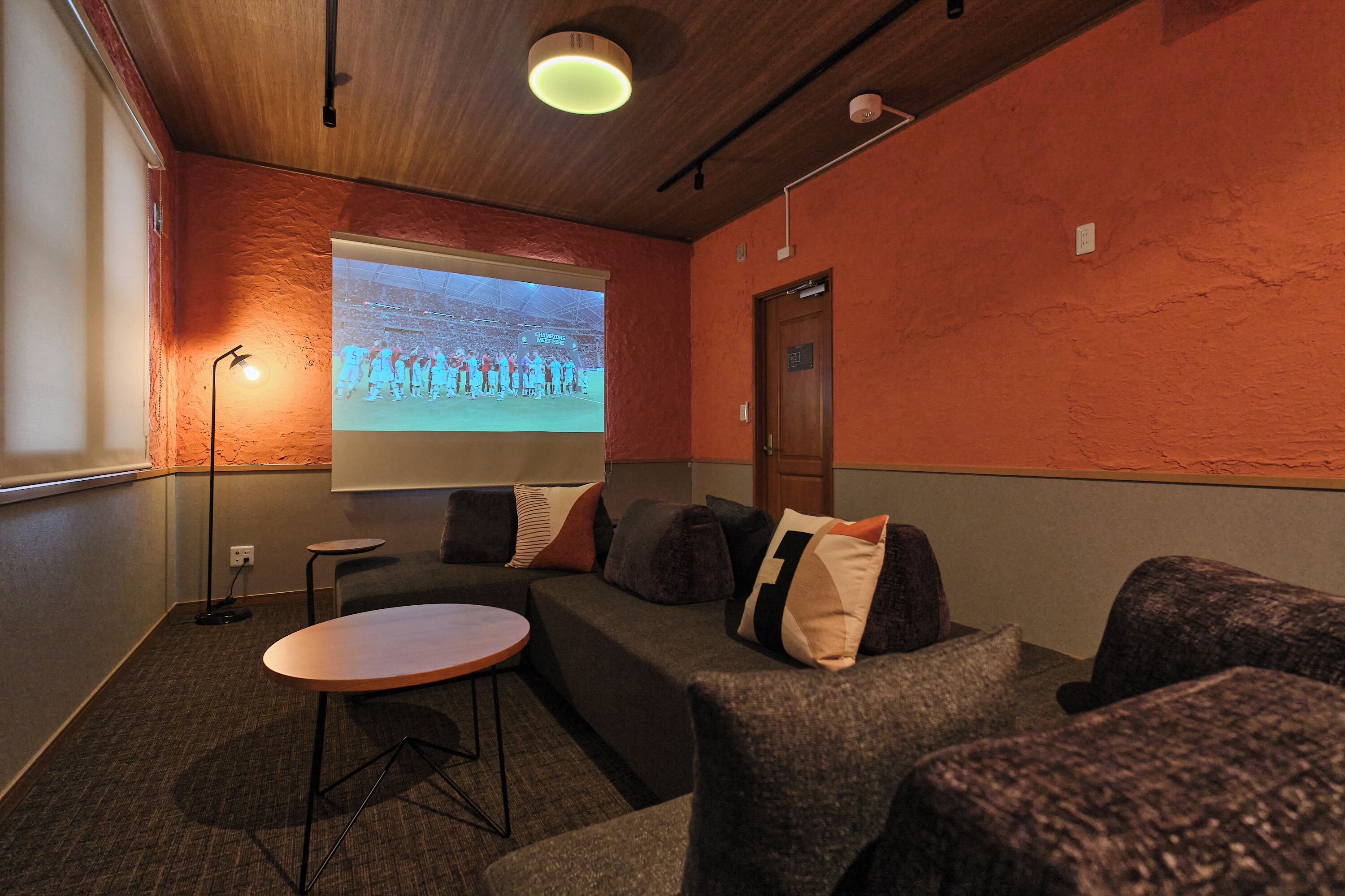 Una sala de conferències amb una pantalla gran, una taula rodona i un sofà.