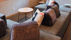 Una habitación con sofá, sillas, una mesita y una lámpara.