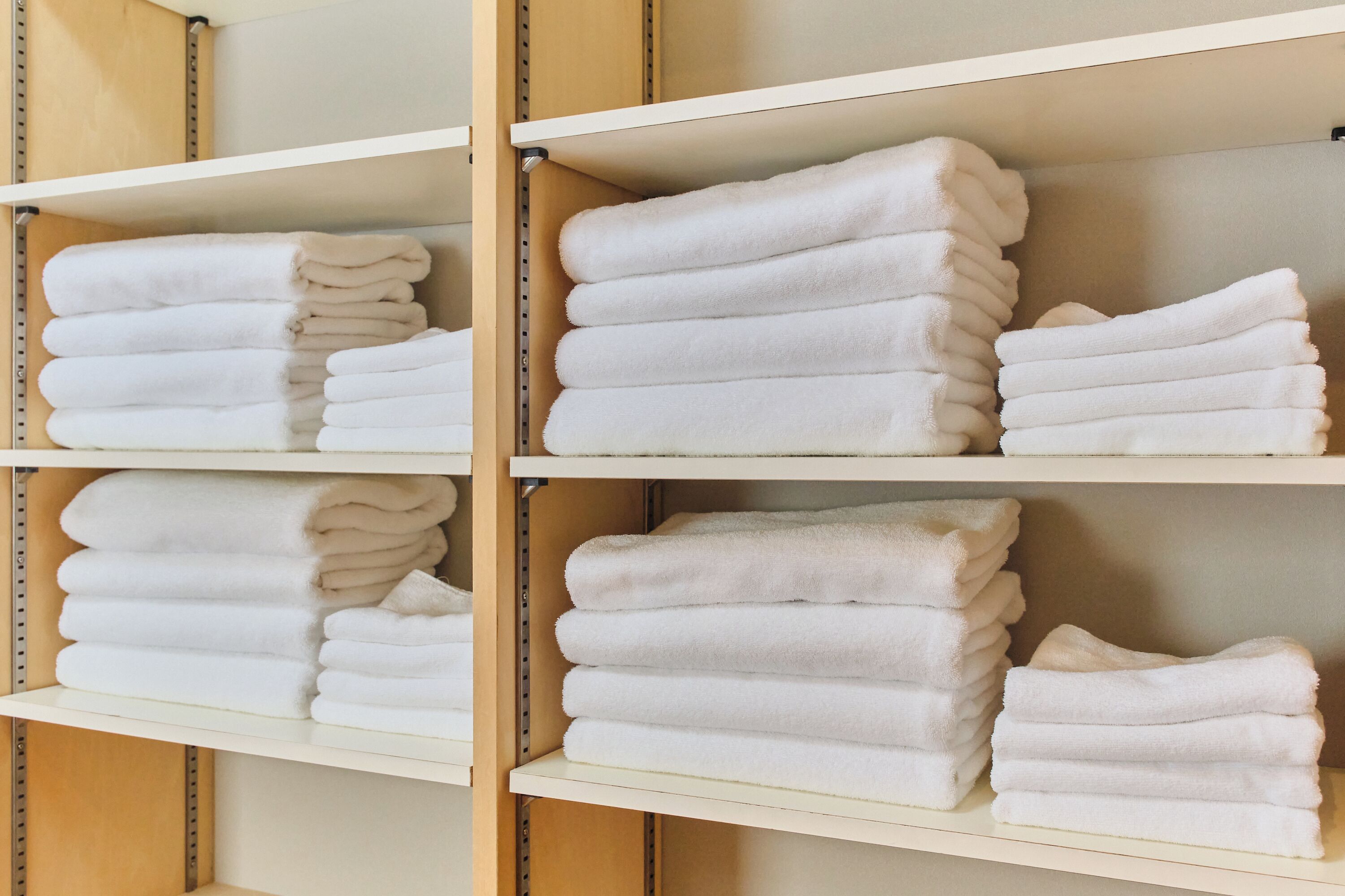 A storage area with shelves holding neatly folded white towels.