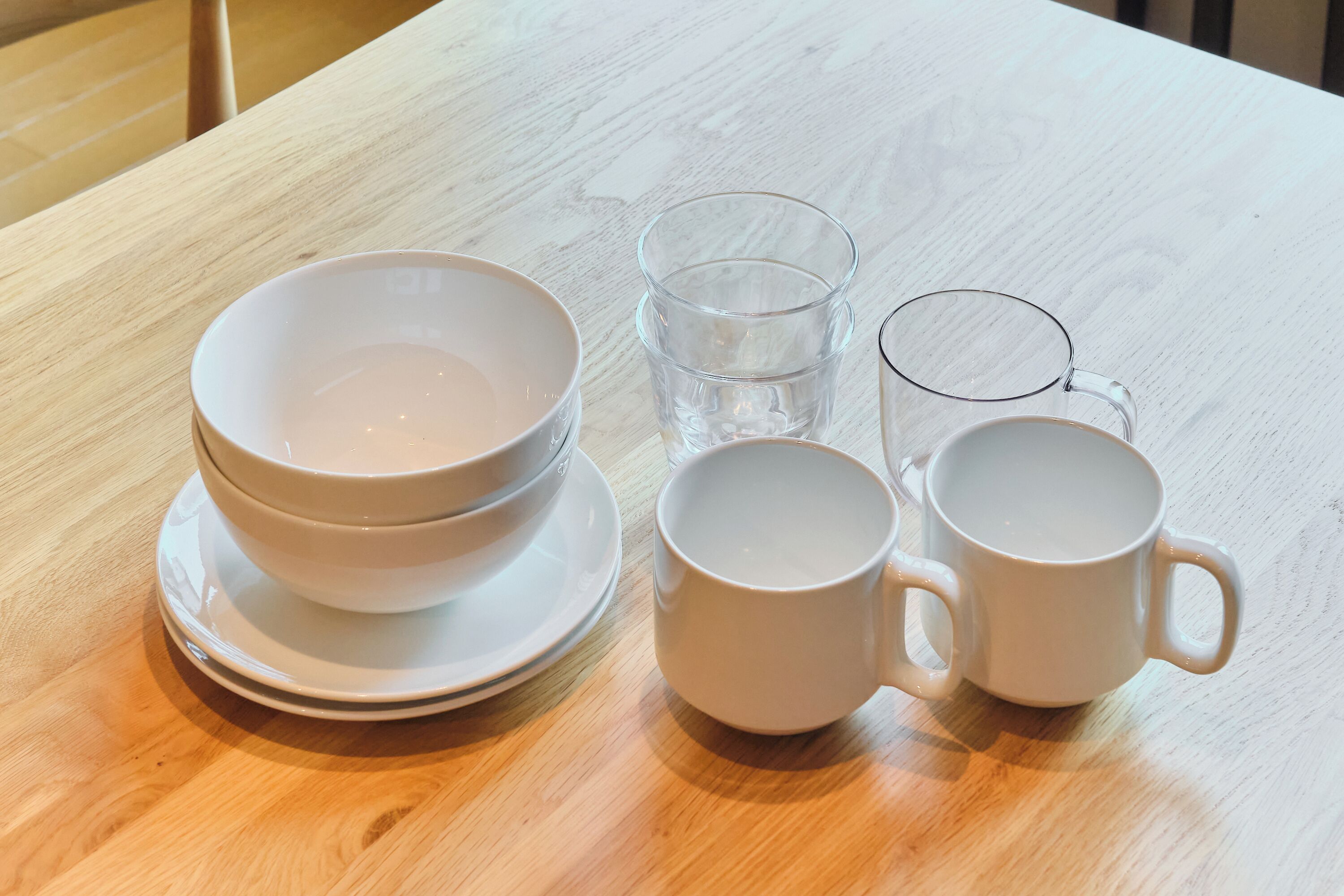 Conjunto de tigelas e xícaras brancas sobre uma mesa de madeira.