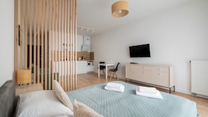 A modern hotel room with a bed, a desk, a TV, and a kitchenette. - Business Park Classy Elegant Studio (Warszawa)