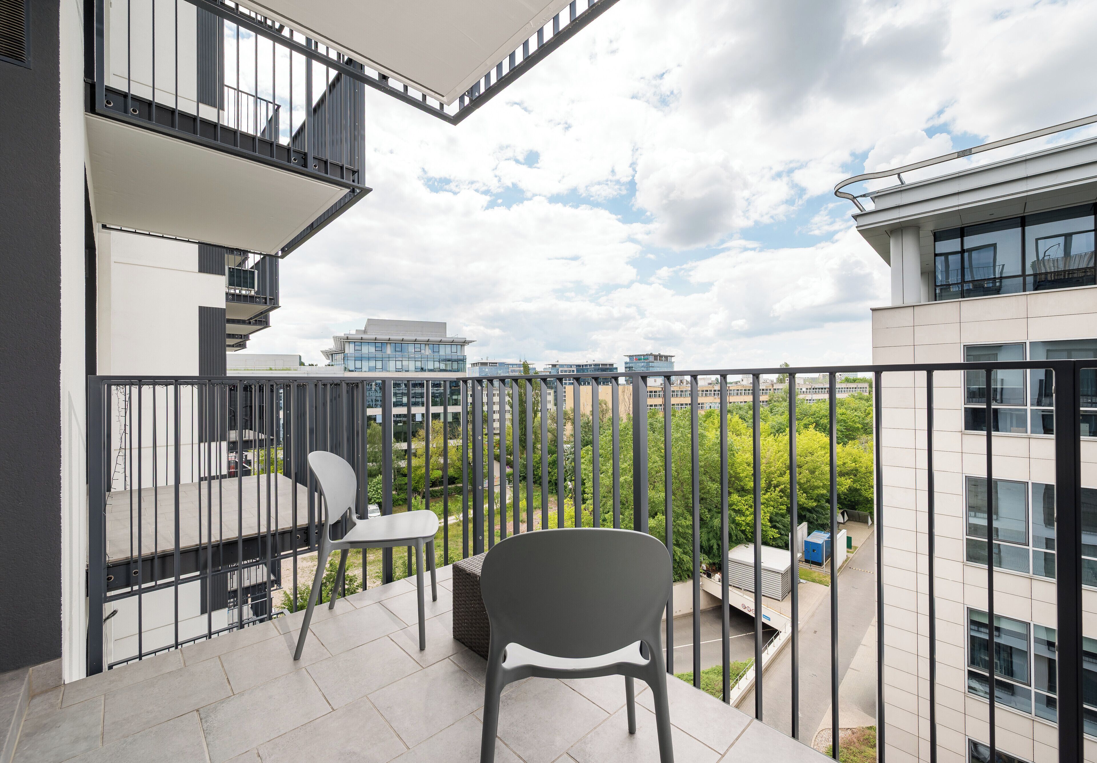 Un balcon avec une chaise, une petite table et une rambarde.