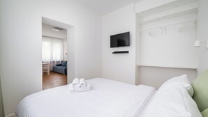 Habitación de hotel con cama, televisor montado en la pared, una mesita y un área de descanso con sofá y sillones.