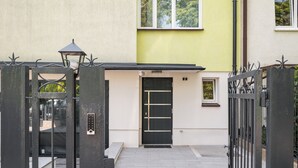 Una entrada protegida con una puerta negra, una ventana pequeña y una reja de metal.