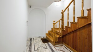 Una escalera con barandillas de madera y suelo con diseño de mármol.
