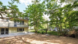 A two-story building with a balcony, surrounded by trees and a fenced yard. - Metro Służew Apartment #2 (Warszawa)