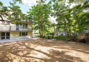 A two-story building with a balcony, surrounded by trees and a fenced yard. - Metro Służew Apartment #2 (Warszawa)