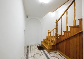 Escada com corrimãos de madeira e chão com padrão marmorizado.