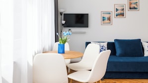 Una sala de estar moderna con sofá, sillas, televisor y cuadros en la pared.