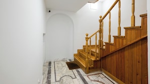 Una escalera con barandillas de madera y suelo con diseño de mármol.