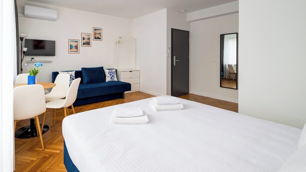Una habitación de hotel moderna con una cama grande, un escritorio con una silla, un sofá y un televisor de pantalla plana.
