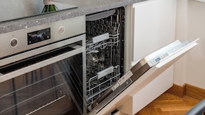 Una cocina equipada con lavavajillas, horno y una estantería empotrada para vinos.