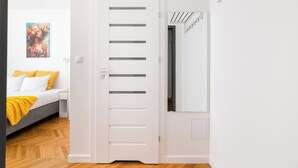 Ein Schlafzimmer mit Bett, Nachttisch, einem Gemälde und einer weißen Tür mit Lamellen.