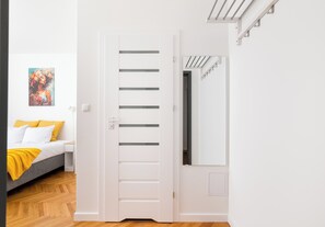 Un dormitorio con cama, mesita de noche, un cuadro y una puerta blanca con listones horizontales.