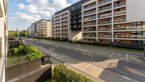 A modern apartment building with multiple balconies, a parking area, and a clear sky. - Tauron Arena Harmony Apartment (Kraków)