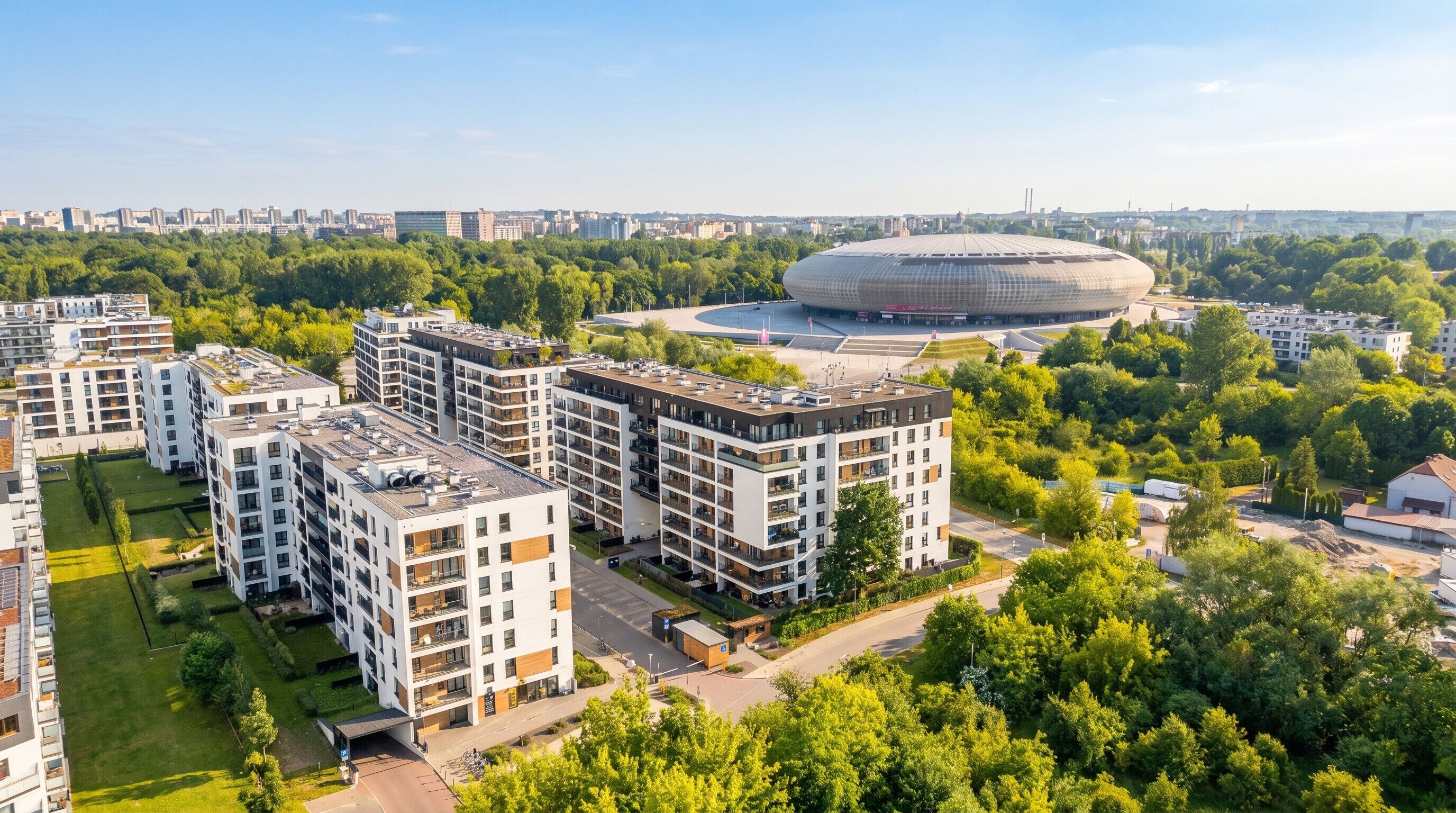 A modern apartment complex with multiple buildings, a central courtyard, and a large stadium in the background.