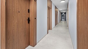 Un pasillo largo y estrecho con puertas de madera a un lado y una pared lisa al otro.