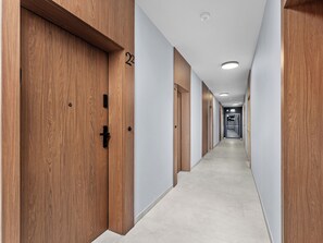 A long, narrow hallway with wooden doors on one side and a plain wall on the other. - Kraków Główny Superior Studio (Kraków)