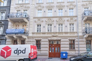 A building with ornate architectural details, a blue banner with contact information, and a delivery van parked in front. - Chopina Stylish Apartment (Katowice)