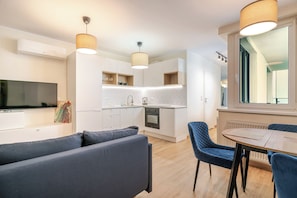 A modern kitchen with white cabinets, a built-in oven, and a window with a view. - Chopina Stylish Apartment (Katowice)
