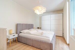 A bedroom with a bed, bedside tables, a wardrobe, and a window. - Chopina Stylish Apartment (Katowice)