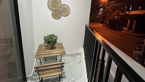 A balcony with a wooden table and chairs, a potted plant, and a decorative wall piece. - Beautiful apartment in the city center (Santo Domingo)