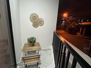 A balcony with a wooden table and chairs, a potted plant, and a decorative wall piece. - Beautiful apartment in the city center (Santo Domingo)