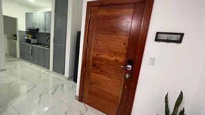 A wooden door with a metal handle, a kitchen area with grey cabinets, and a sign on the wall. - Beautiful apartment in the city center (Santo Domingo)