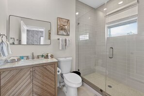 Un bagno moderno con cabina doccia in vetro, lavabo in marmo e mobile contenitore in legno.