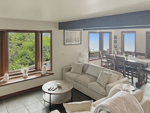 A living room with a sofa, a round coffee table, and a dining area with a table and chairs.
