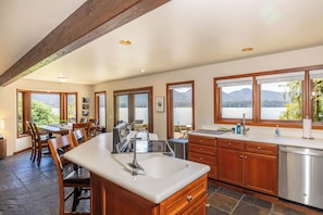A kitchen with a large island, wooden cabinets, and a view of mountains.
