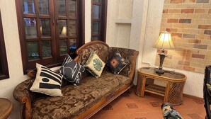 A traditional sofa with patterned cushions, a small side table with a lamp, and a tiled floor. - Amango Village (Ho Chi Minh City)