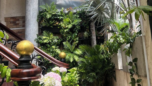 A narrow outdoor corridor with a wooden staircase, potted plants, and a metal railing. - Amango Village (Ho Chi Minh City)