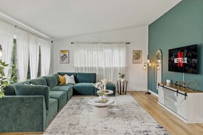 A modern living room with a sectional sofa, a coffee table, a TV, and a console table.