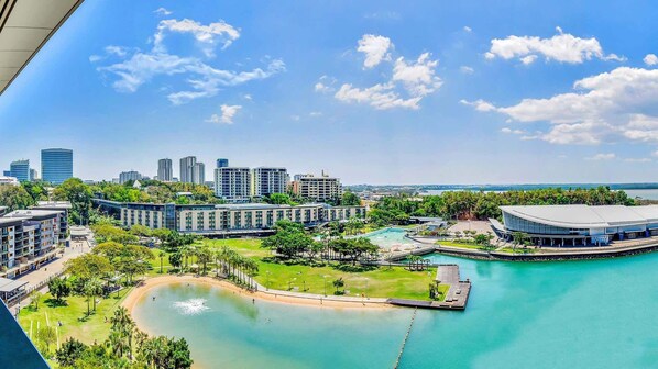 A coastal resort with a marina, modern buildings, and a large pool area.