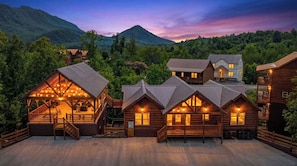 A log cabin resort with multiple buildings, outdoor seating, and a scenic mountain backdrop. - Sleeps 30 | Heated Pool | Arcade, Game Room & Theater | Mtn Views (seveirville)