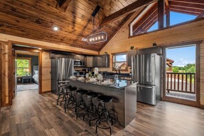 A spacious kitchen with a central island, stainless steel appliances, and a view to the outdoors. - Sleeps 30 | Heated Pool | Arcade, Game Room & Theater | Mtn Views (seveirville)