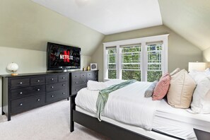 Ein Schlafzimmer mit Bett, Schminktisch, Fernseher und Fenster.