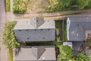 Eine Vogelperspektive eines Wohngebiets mit Häusern, einer asphaltierten Straße und Grünflächen.