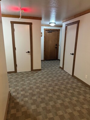 A hallway with carpeted floors, wooden doors, and a ceiling fan. - Spacious + Pet Friendly + Walk to Village - 2/2 (Mammoth Lakes)