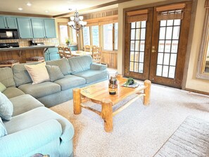 A living room with a sectional sofa, a wooden coffee table, and a dining area with a wooden table and chairs. - Spacious + Pet Friendly + Walk to Village - 2/2 (Mammoth Lakes)