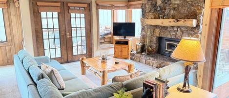 A cozy living room with a stone fireplace, a television, and a comfortable seating area.