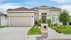 A two-story house with a garage, a front door, and a mailbox. - Spacious, Comfortable Texas Stay for Extended Business & Family Visits. (Pharr)