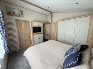 Un dormitorio con cama, televisor, armario y radiador.